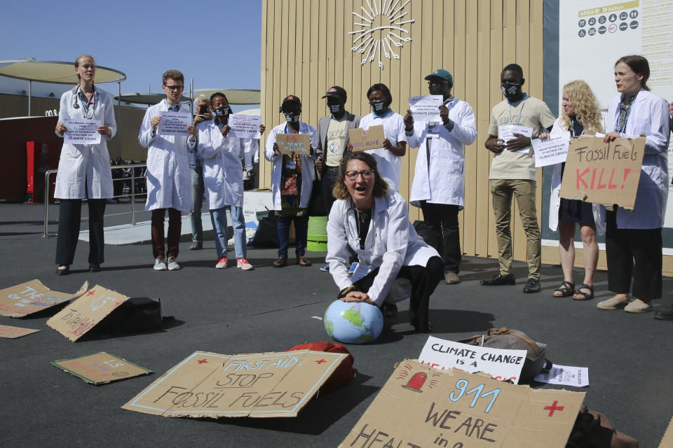 A medical worker performs a symbolic "artificial respiration" on a globe as health care workers from various countries perform a "die-in" to protest the effect of climate change on health issues at the COP27 U.N. Climate Summit, Friday, Nov. 11, 2022, in Sharm el-Sheikh, Egypt. (AP Photo/Thomas Hartwell)