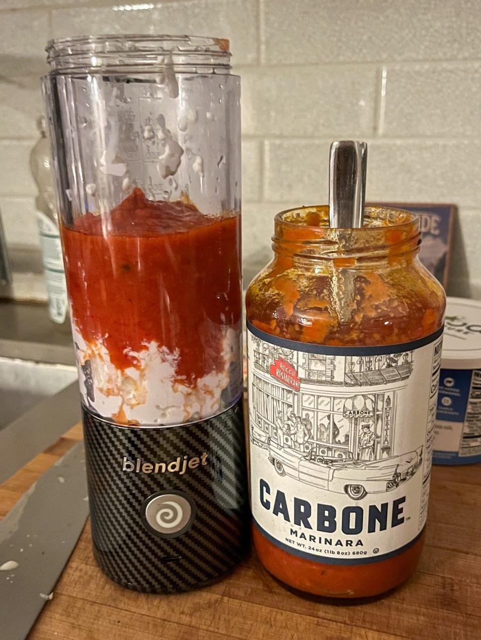 A blender with marinara sauce and cottage cheese next to a jar of Carbone sauce.