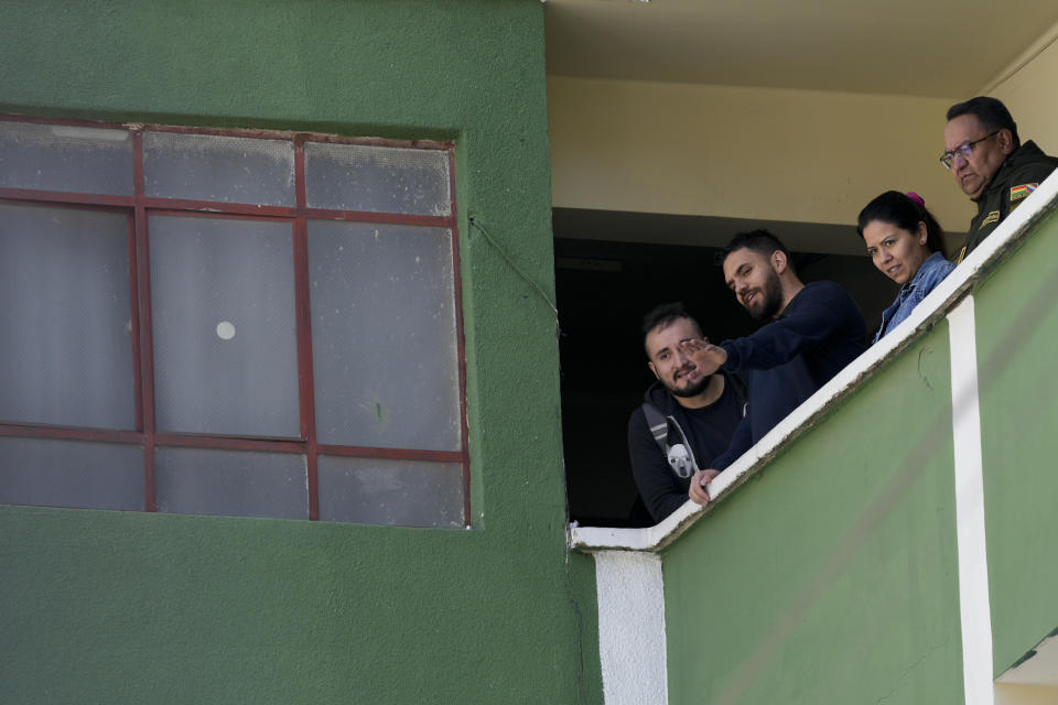 Senior Cabinet member Eduardo del Castillo, second left, waves from a balcony police station as people detained for their involvement in what President Luis Arce called a coup attempt are escorted from their jail cells to be taken to the Chonchocoro maximum security prison, in La Paz, Bolivia, Saturday, June 29, 2024. (AP Photo/Juan Karita)