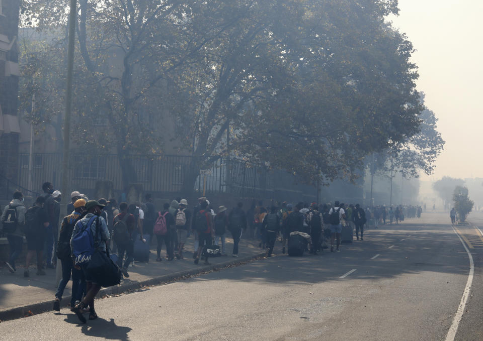 Students make their way after being evacuated from their residence at the University of Cape Town, South Africa, Sunday, April 18, 2021. A wildfire raging on the slopes of the mountain forced the evacuation and caused damage to several buildings as firefighters battled the blaze. (AP Photo/Nardus Engelbrecht)