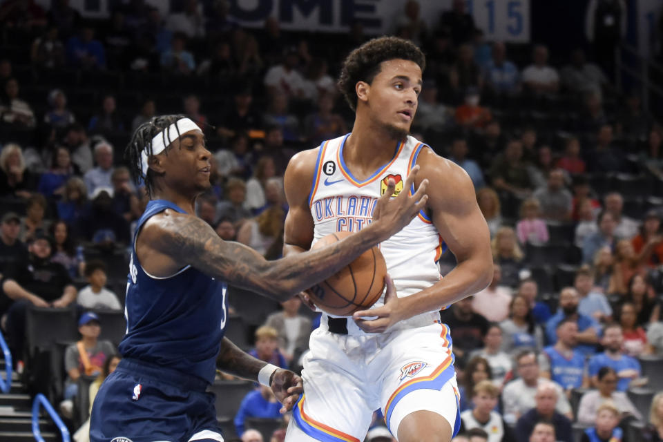 Minnesota Timberwolves forward Jaden McDaniels, left, tries to get the ball away from Oklahoma City Thunder center Jeremiah Robinson-Earl, right, in the first half of an NBA basketball game, Sunday, Oct. 23, 2022, in Oklahoma City. (AP Photo/Kyle Phillips)