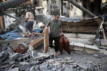 A Palestinian salvages belongings from a damaged home, which police said was targeted in an Israeli air strike, in Gaza City July 17, 2014. REUTERS/Finbarr O'Reilly