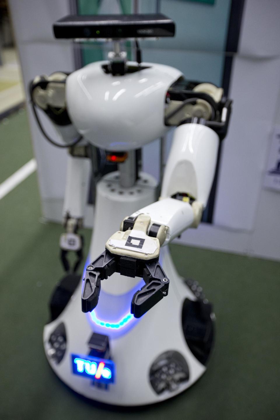 Amigo, a white robot the size of a person, uses information gathered by other robots to move towards a table to pick up a carton of milk and deliver it to an imaginary patient in a mock hospital room at the Technical University of Eindhoven, Netherlands, Wednesday Jan. 15, 2014. A group of five of Europe's top technical universities, together with technology conglomerate Royal Philips NV, are launching an open-source system dubbed "RoboEarth" Thursday. The heart of the mission is to accelerate the development of robots and robotic services via efficient communication with a network, or "cloud". (AP Photo/Peter Dejong)