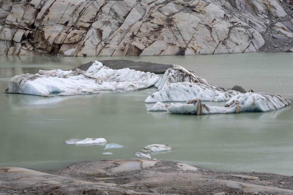 Chunks of ice covered by sheets float in a lake at the Rhone Glacier near Goms, Switzerland, Friday, June 16, 2023. The sheets are just a small scale solution and Alpine glaciers are still expected to vanish by the end of the century. (AP Photo/Matthias Schrader)