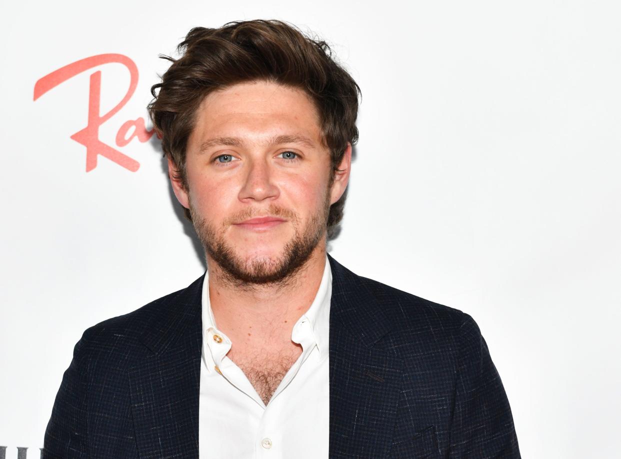 Niall Horan looks amazing in a well tailored dark blue suit with white inner T-shirt.