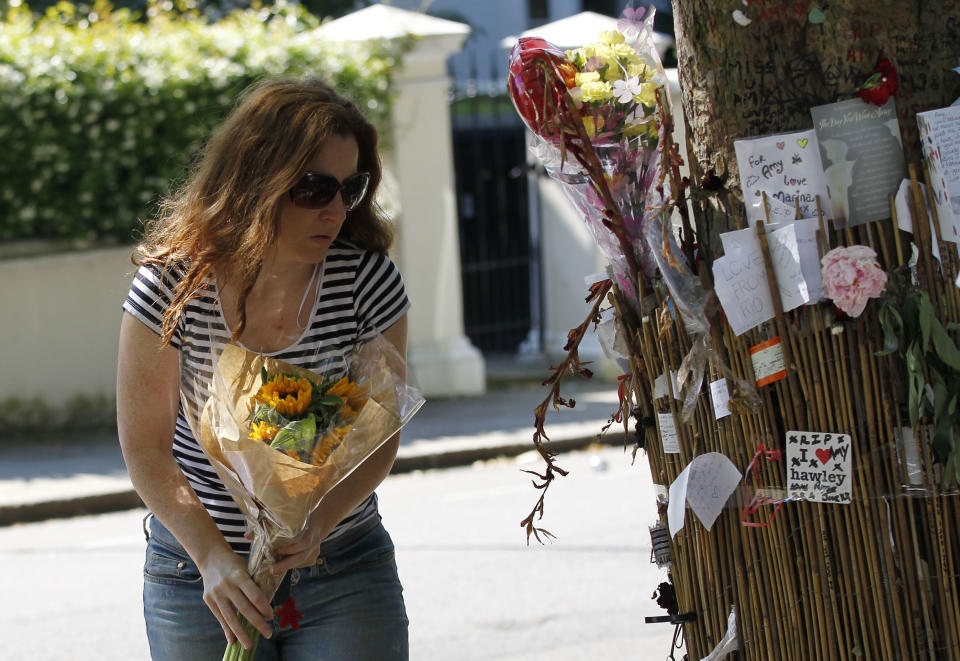 A fan of British singer songwriter Amy Winehouse leaves flowers for her outside her house in London on the first anniversary of her death, Monday, July 23, 2012. (AP Photo/Sang Tan)