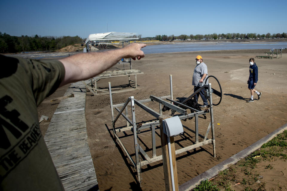 Residents walk past boating docks that sit still after water washed out of Wixom Lake due to the failure of the Edenville Dam on Wednesday, May 20, 2020 in Edenville Township north of Midland, Mich. (Jake May/The Flint Journal, MLive.com via AP)