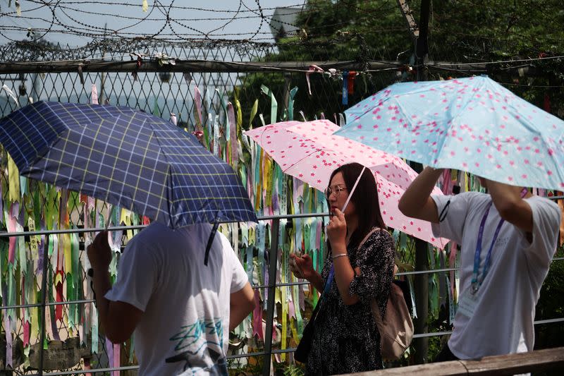 Foreign tourists participating in DMZ tour walk past a military fence near the demilitarized zone separating the two Koreas, in Paju