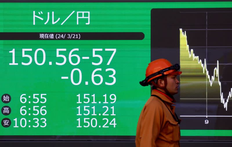 A man walks past an electric screen displaying the current Japanese Yen exchange rate against the U.S. dollar outside a brokerage in Tokyo