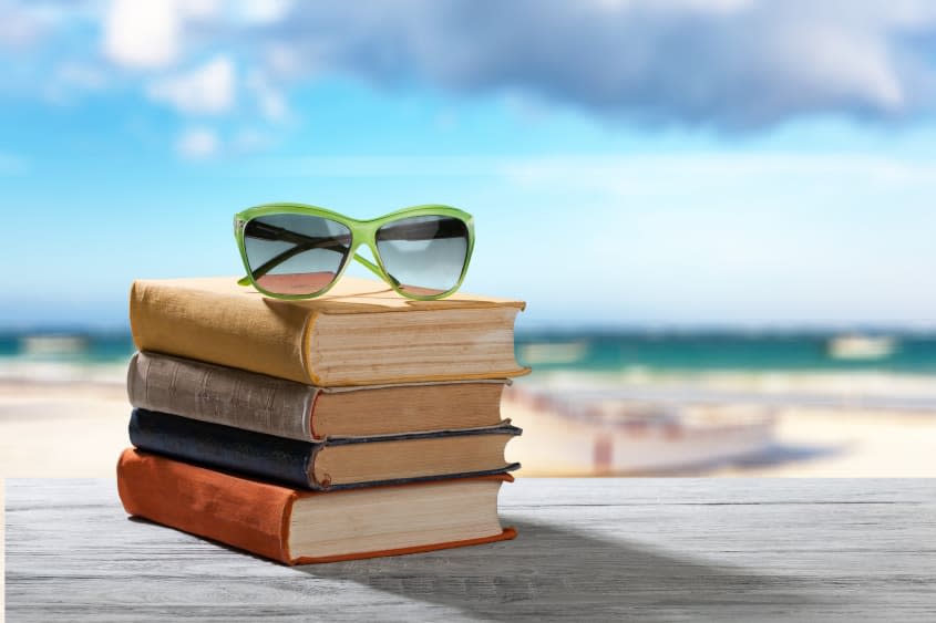 Books and sunglasses on beach background