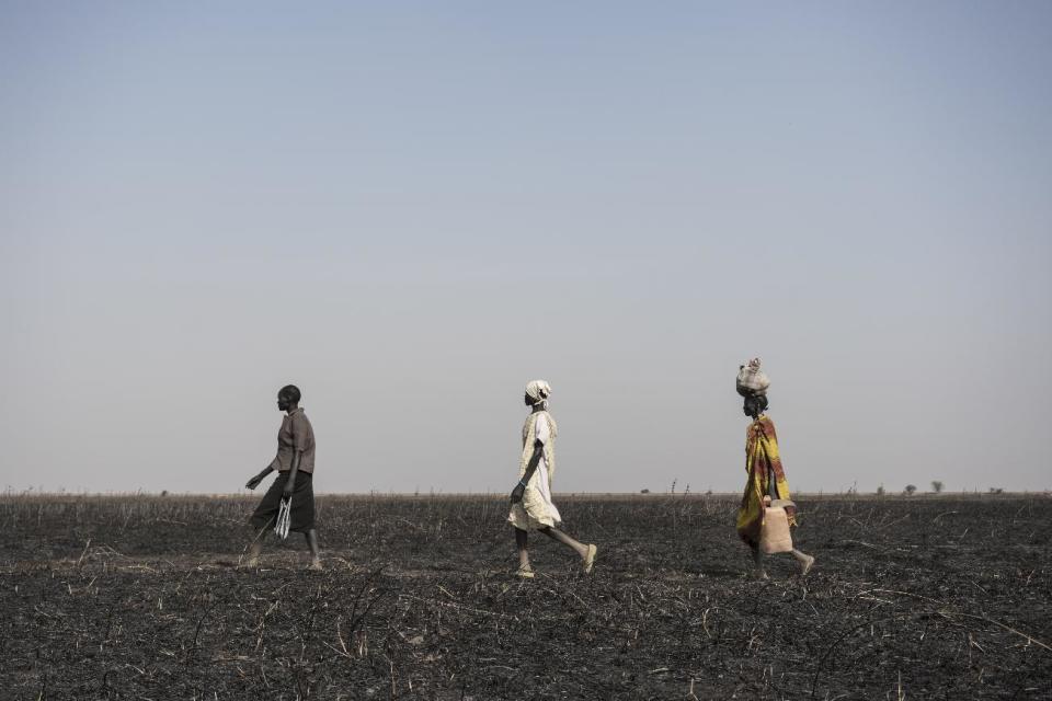 In this photo taken Saturday, March 11, 2017, women walk across parched and burned former farmland on the outskirts of Aweil, in South Sudan. As World Water Day approaches on March 22, more than 5 million people in South Sudan, do not have access to safe, clean water, compounding the problems of famine and civil war, according to the UNICEF. (Mackenzie Knowles-Coursin/UNICEF via AP)