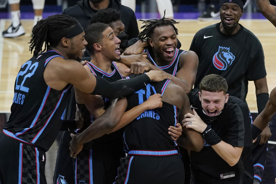 Sacramento Kings forward Harrison Barnes, foreground middle, is congratulated by teammates after shooting the game-winning 3-point basket in the team's NBA basketball game against the Cleveland Cavaliers in Sacramento, Calif., Saturday, March 27, 2021. (AP Photo/Jeff Chiu)