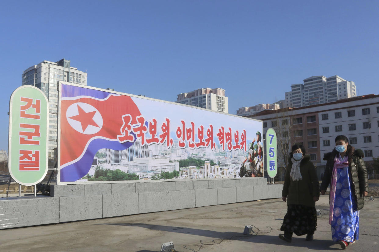 People walk on a street of Pothonggang District in Pyongyang, North Korea Wednesday, Feb. 8, 2023, on the 75th founding anniversary of the Korean People's Army (KPA). The sign reads "Defending country, people and revolution. Day of KPA Foundation." (AP Photo/Cha Song Ho)