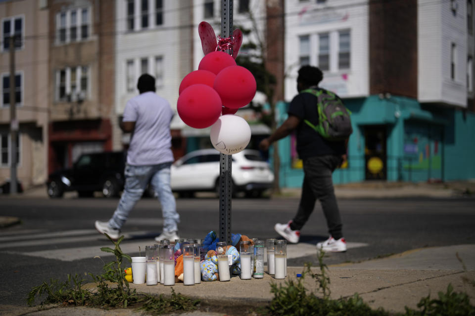 People walk past a memorial for Dymir Stanton, 29, a victim of a fatal shooting spree, Thursday, July 6, 2023, in Philadelphia. The shooting left five people dead and four others wounded Monday night. (AP Photo/Matt Slocum)