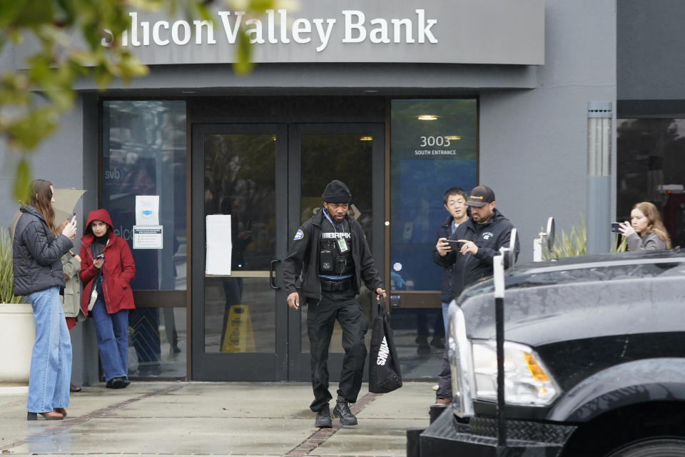 A Brinks worker walks toward a truck after exiting Silicon Valley Bank in Santa Clara, Calif., Friday, March 10, 2023. The U.S rushed to seize the assets of Silicon Valley Bank on Friday after a run on the bank, the largest failure of a financial institution since Washington Mutual during the height of the financial crisis more than a decade ago. (AP Photo/Jeff Chiu)