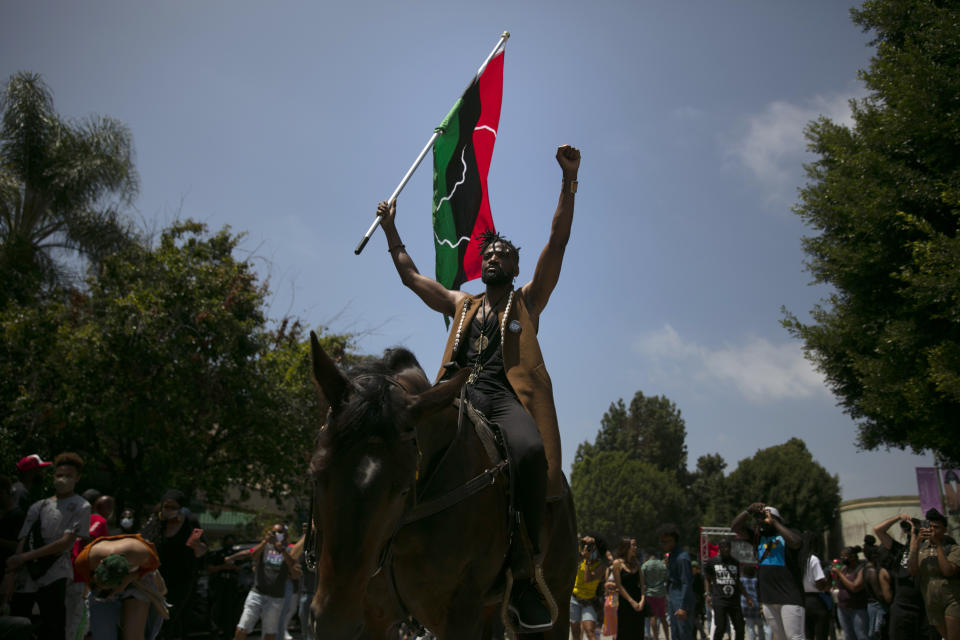 Rein Morton clenches his fist while carrying a Pan-African flag on horseback during a Juneteenth celebration in Los Angeles, Friday, June 19, 2020. Juneteenth is the holiday celebrating the day in 1865 that enslaved Black people in Galveston, Texas, learned they had been freed from bondage, more than two years after the Emancipation Proclamation. (AP Photo/Jae C. Hong)