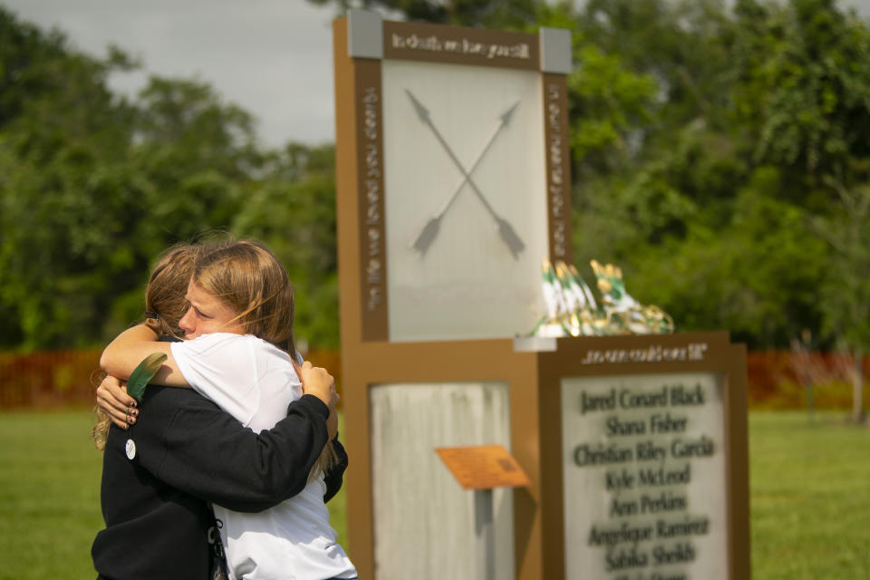 Chailyn Gillespie, who is graduating from Santa Fe High School this year, hugs a friend next to the new memorial to the ten victims of the 2018 shooting at the high school, following a dedication ceremony, Tuesday, May 18, 2021, outside of the high school in Santa Fe. The Santa Fe Ten Memorial Foundation unveiled the "Unfillable Chair," a student designed memorial, on the third anniversary of the shooting. The foundation is planning a larger memorial for the future. (Mark Mulligan/Houston Chronicle via AP)