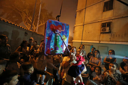 A woman holds a child as they get ready to hit a pinata at a birthday party celebration in Caracas,Venezuela, April 13, 2019. REUTERS/Ivan Alvarado