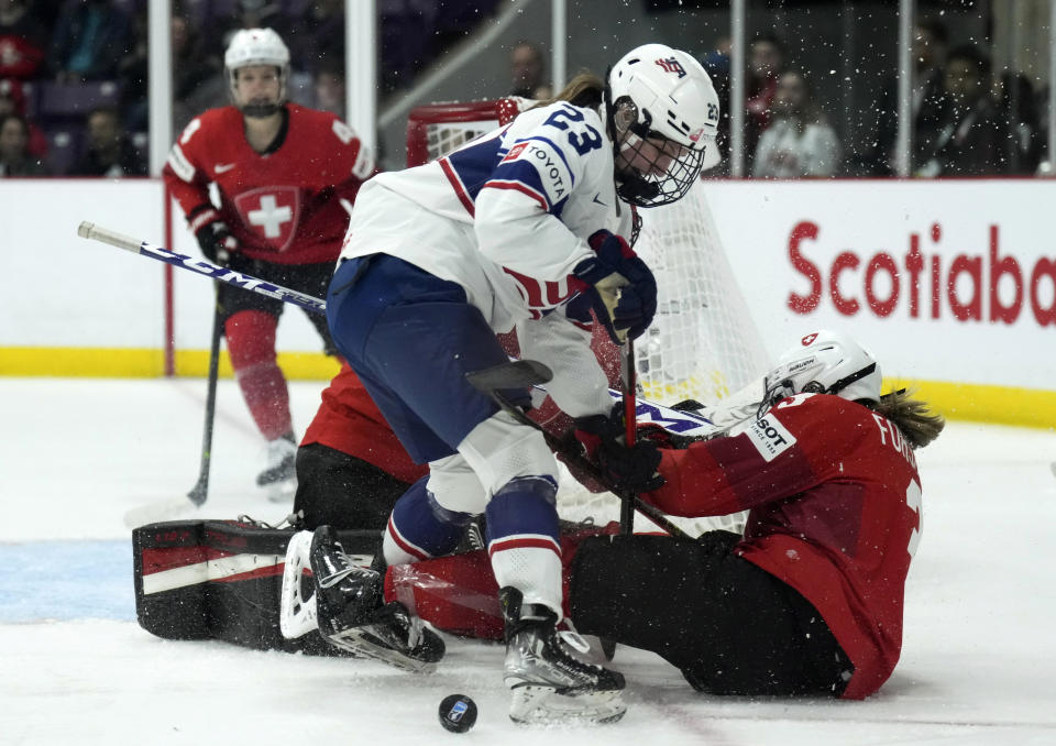 United States forward Hannah Bilka (23) battles for the loose puck against Switzerland defender Sarah Forster (3) during the first period of a match at the Women's World Hockey Championships in Brampton, Ontario, Friday, April 7, 2023. (Nathan Denette/The Canadian Press via AP)