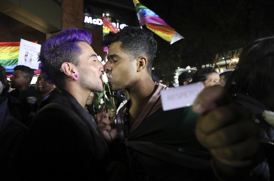 A same sex couple kiss a rose during a "Kiss-a-thon," as a form of protest for LGBT rights in Bogota, Colombia, Wednesday, April 17, 2019. The event was held at the same Andino shopping mall where days ago two gay men were harassed by a customer who lured police into fining them for "exhibitionism." (AP Photo/Fernando Vergara)