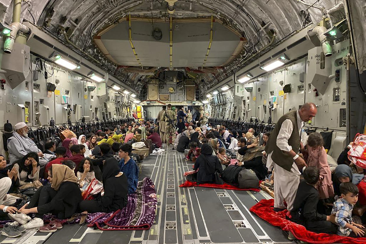 Afghan people sit inside a U.S. military aircraft preparing to leave Afghanistan. (Shakib Rahmani/AFP via Getty Images)