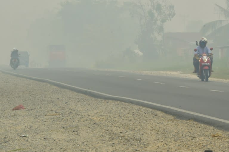 Motorists drive down a street as haze shrouds the area in Pekanbaru, Indonesia's Riau province, on September 14, 2015