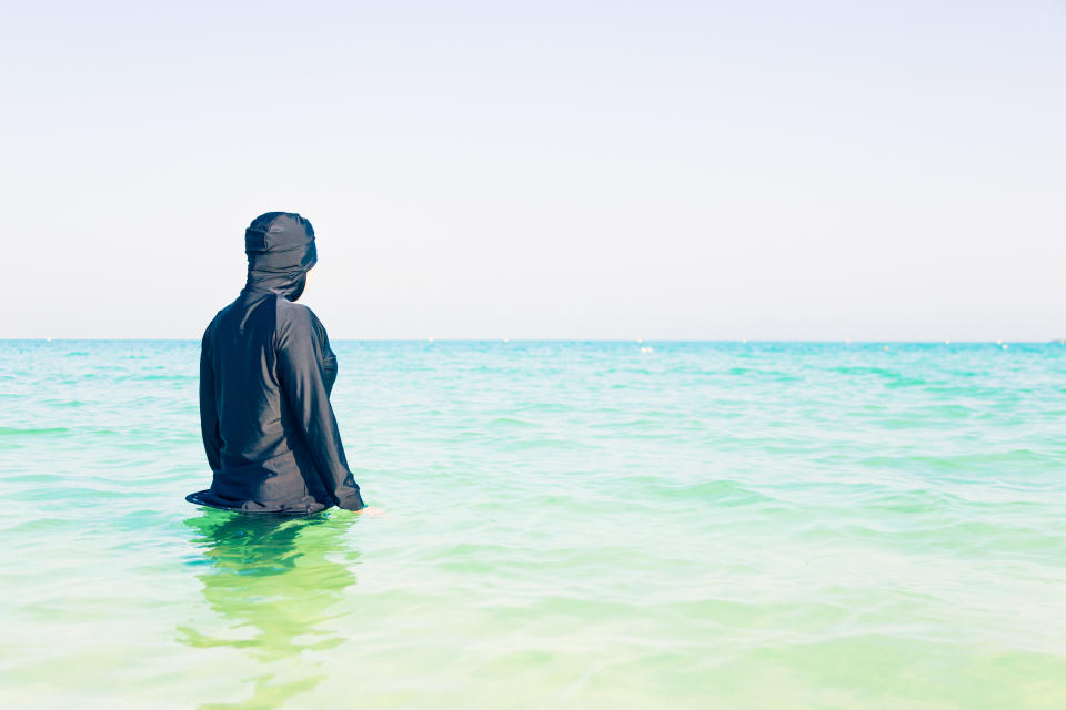 young woman in burkini swimming in the sea, persian gulf, jumeirah beach in dubai