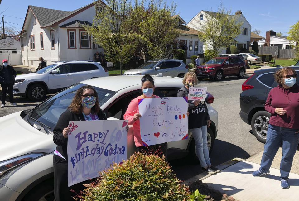 Friends and family have gathered at a social distance to help Jennifer DeSena celebrate her 60th birthday, Saturday, May 2, 2020, in Long Beach, N.Y., during the coronavirus pandemic. DeSena stood on her front porch for the party. (AP Photo/Mark Lennihan)