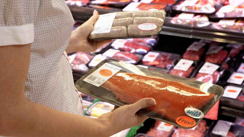 Person holding supermarket fish filet and sausage