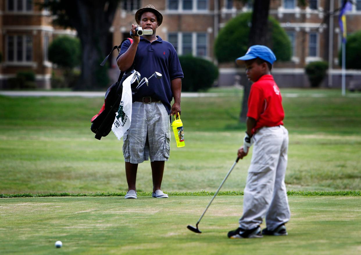 July 25, 2012 - Jeremy Johnson (left) videos his son Daniel Johnson, 8, (right) as he putts during the 67th Overton Park Junior Open golf tournament in Overton Park Wednesday afternoon.