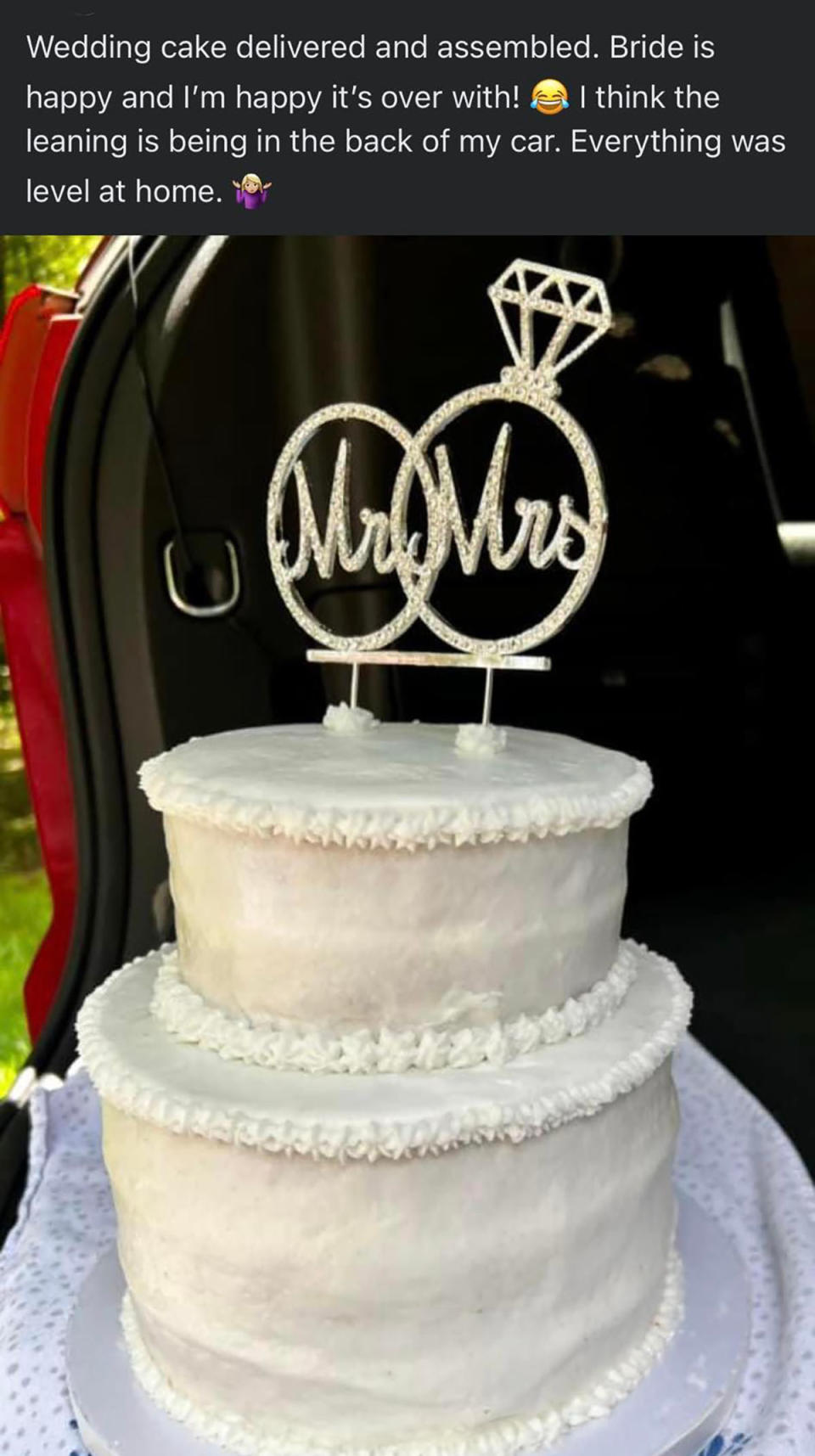 Lopsided, lumpy white wedding cake in the back of the car, with a Mr and Mrs topper. 