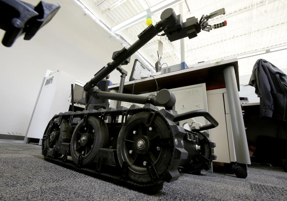 In this Aug. 28, 2018 photo a Centaur robot rests on a carpeted floor between desks at Endeavor Robotics in Chelmsford, Mass. The Army is looking for a few good robots. These robots won’t fight, at least not yet. But they will be designed to help the men and women who do. The companies making them are waging a different kind of battle. At stake is a contract worth almost half a billion dollars for 3,000 backpack-sized robots that can defuse bombs and scout enemy positions. (AP Photo/Steven Senne)