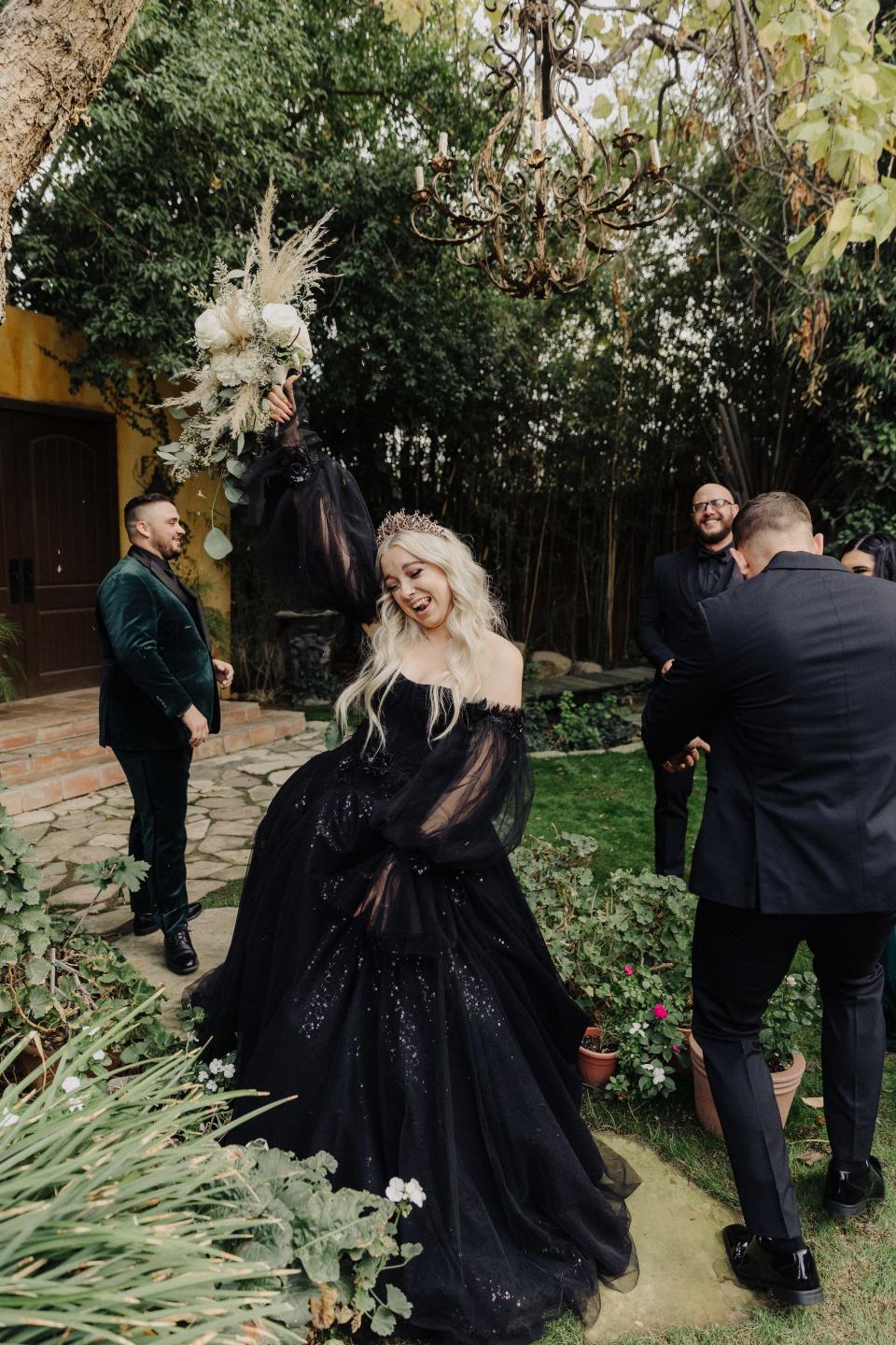 A bride raises her bouquet in the air in excitement.