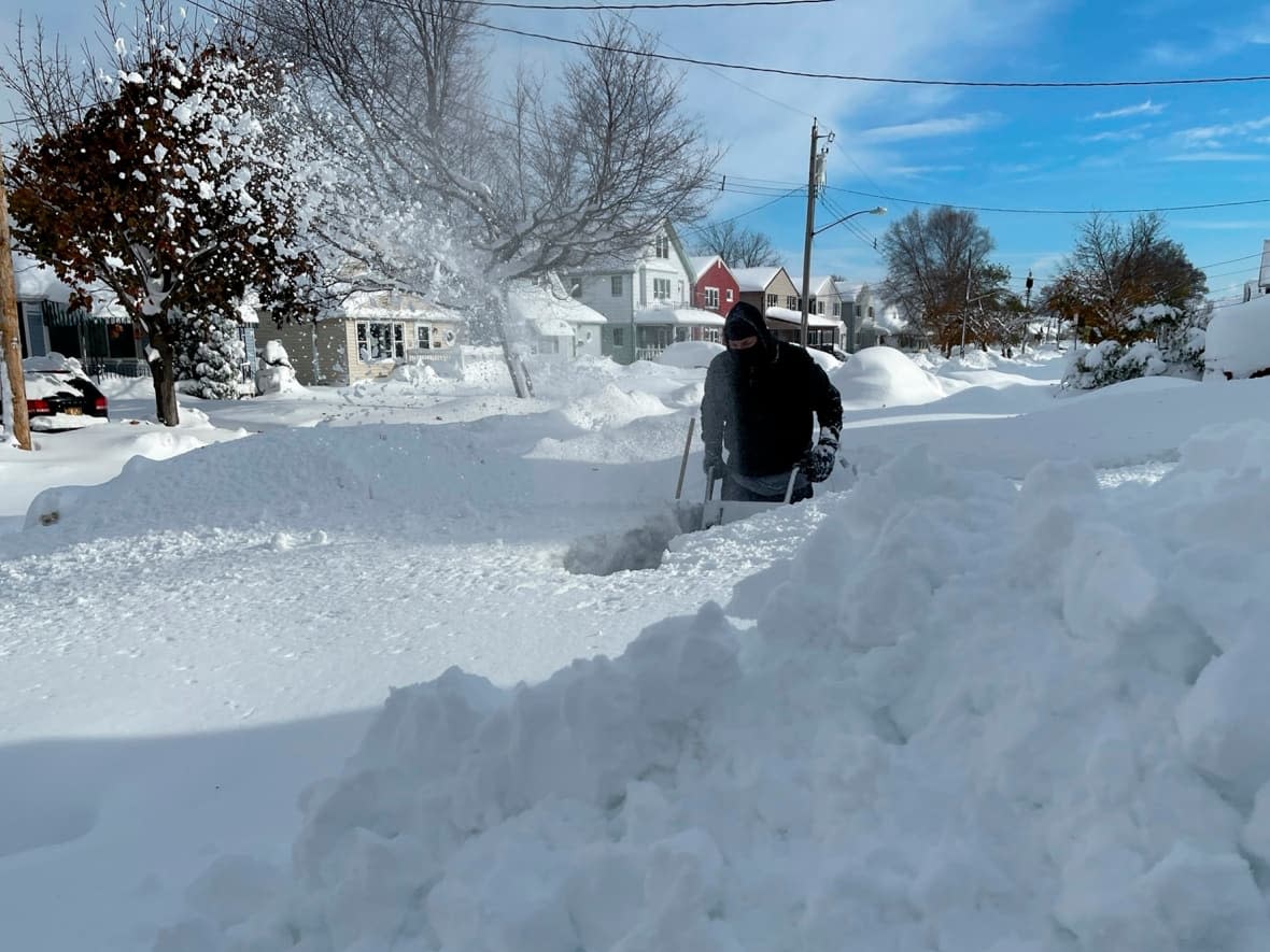 Martin Haslinger uses a snowblower outside his home in Buffalo, N.Y.,  on Saturday, Nov. 19, 2022 following a lake-effect snow event.  Residents of northern New York state are digging out after nearly two metres of snow fell in some areas and caused three deaths. (Bridget Haslinger/The Associated Press - image credit)