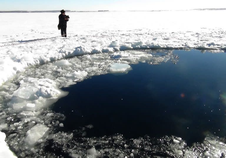 A police officer looks at a hole in a lake near Chebakul in Russia's Chelyabinsk region yesterday. Divers scoured the bottom of a Russian lake on Saturday for fragments of a meteorite that plunged to Earth in a blinding fireball whose shockwave injured 1,200 people and damaged thousands of homes