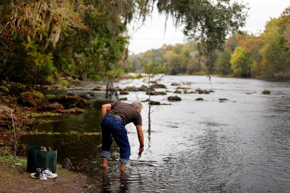 A visitor to the Santa Fe River pulls debris from the shallow water near the public boat basin just off U.S. 441 in High Springs.