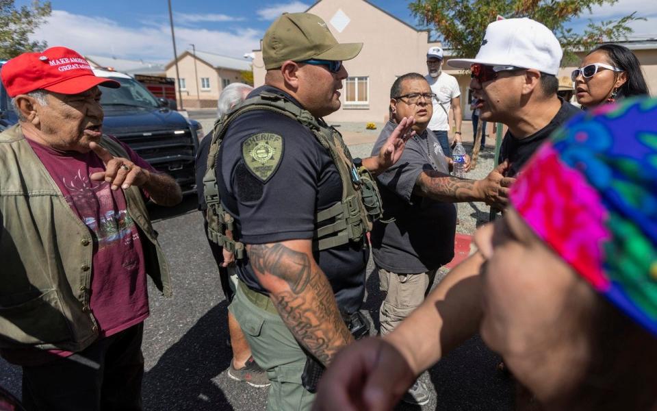 A law enforcement officer stands as protestors clash at the site of a planned installation of a statue of Spanish conquistador Oñate