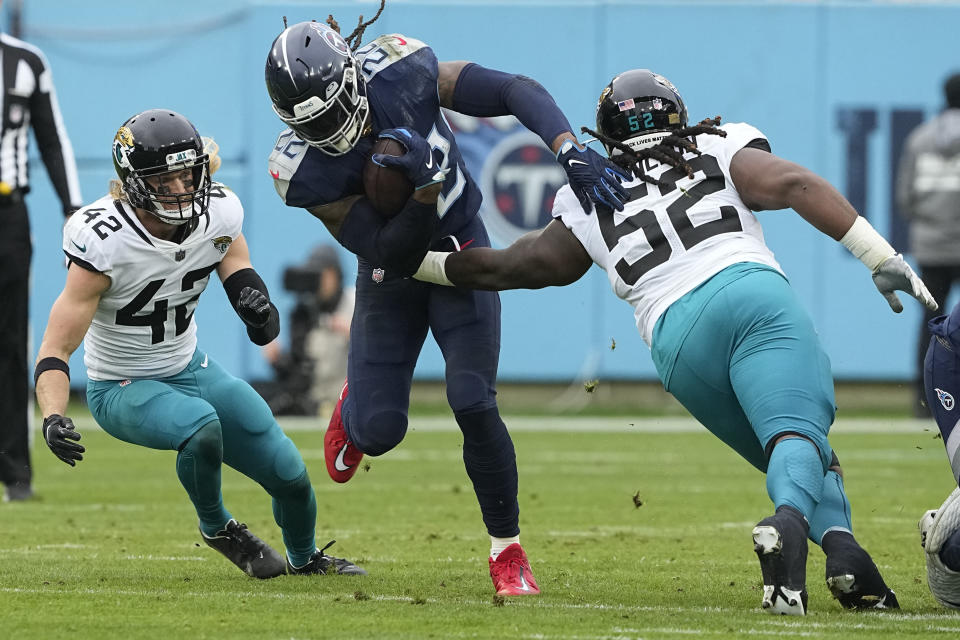 Tennessee Titans running back Derrick Henry (22) runs with the ball as Jacksonville Jaguars safety Andrew Wingard (42) and defensive tackle DaVon Hamilton (52) defend during the first half of an NFL football game Sunday, Dec. 11, 2022, in Nashville, Tenn. (AP Photo/Chris Carlson)