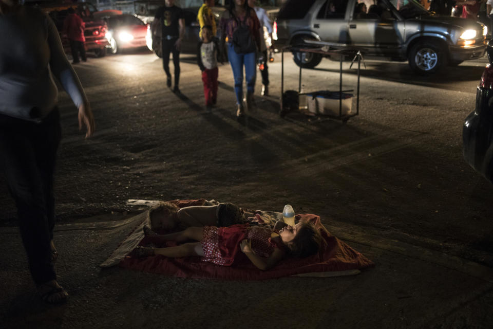 Children sleep in the street near their mother's food stand where she sells food to people attending an event marking the feast day of Our Lady of Chiquinquirá, better know as "Chinita," in downtown Maracaibo, Venezuela, Nov. 17, 2019. For many in Maracaibo, Venezuela's economic crash in the last five years hit especially hard. Once a center of the nation's vast oil wealth, production under two decades of socialist rule has plummeted to a fraction of its high, taking down residents' standard of living. (AP Photo/Rodrigo Abd)