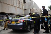 Policemen guard as members of Crime Scene Unit investigate around a car used by alleged gunmen at the main entrance of the Pakistan Stock Exchange building in Karachi on June 29, 2020. - Gunmen attacked the Pakistan Stock Exchange in Karachi on June 29, with four of the assailants killed, police said. (Photo by Asif HASSAN / AFP) (Photo by ASIF HASSAN/AFP via Getty Images)