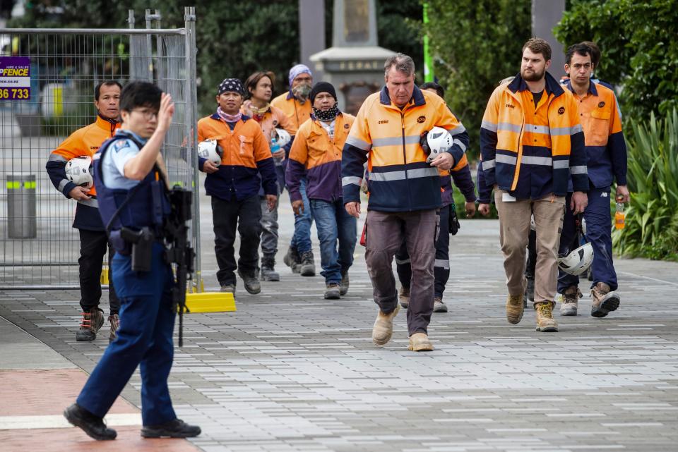 Construction workers are escorted by police in the central business district (AP)