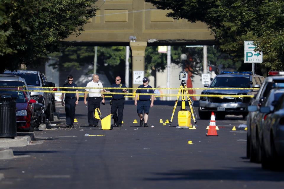 Authorities walk among evidence markers at the scene of a mass shooting, Sunday, Aug. 4, 2019, in Dayton, Ohio. Severral people in Ohio have been killed in the second mass shooting in the U.S. in less than 24 hours, and the suspected shooter is also deceased, police said. (AP Photo/John Minchillo)