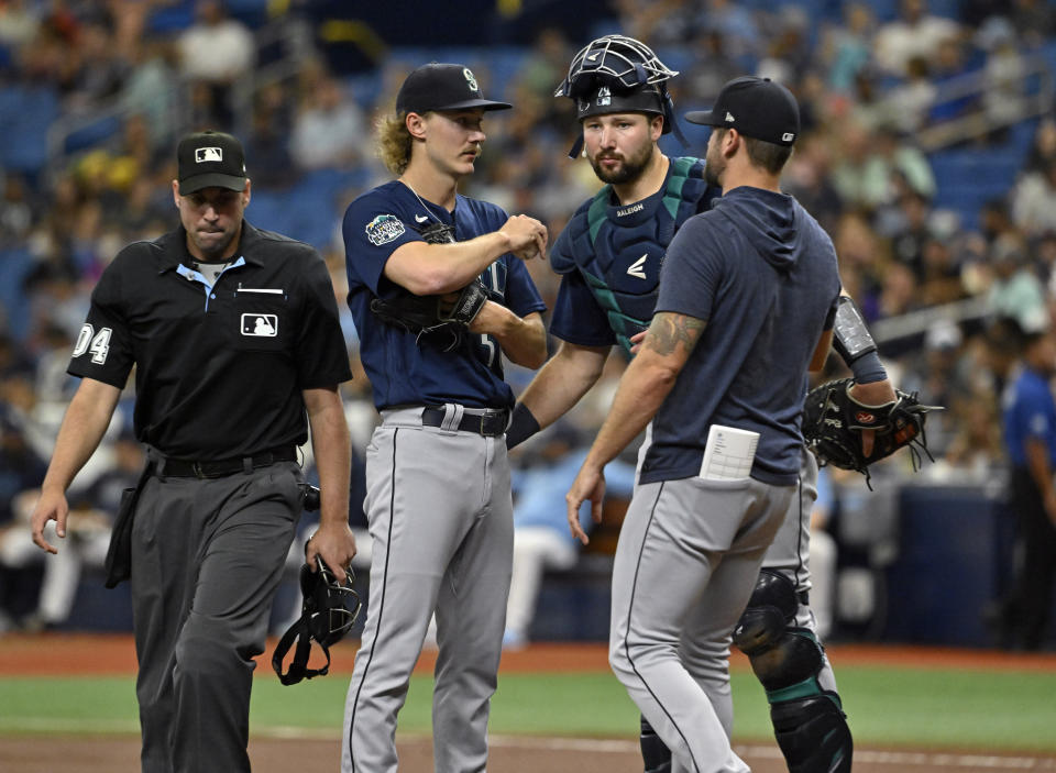 Home plate umpire Paul Clemons, left, breaks up a meeting on the mound between Seattle Mariners starter Bryce Miller, center, catcher Cal Raleigh and pitching coach Pete Woodworth, right, during the first inning of a baseball game against the Tampa Bay Rays, Sunday, Sept. 10, 2023, in St. Petersburg, Fla. (AP Photo/Steve Nesius)