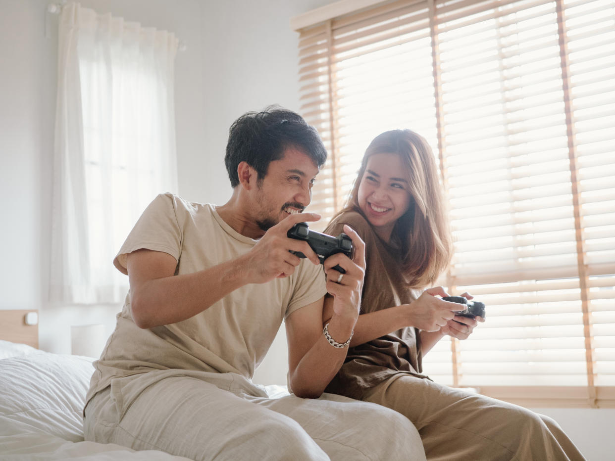 Asian couple having fun playing video games at home