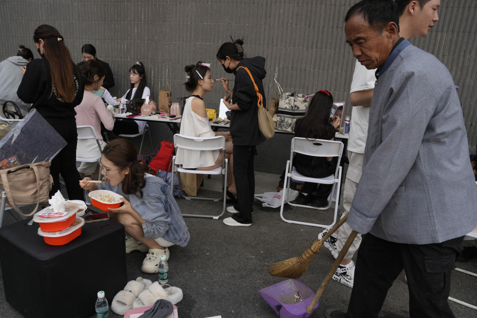 Models put on make up while others take a lunch break during Auto China 2024 in Beijing, Thursday, April 25, 2024. Global automakers and EV startups unveiled new models and concept cars at China's largest auto show on Thursday, with a focus on the nation's transformation into a major market and production base for digitally connected, new-energy vehicles. (AP Photo/Ng Han Guan)