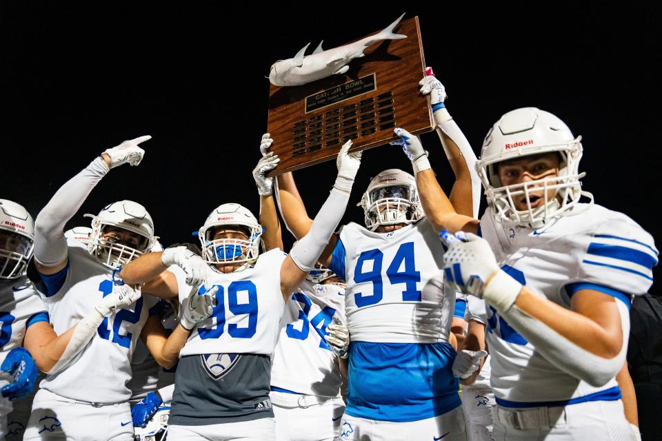 Barron Collier Cougars defensive player Ariel Aguilera (94) raises the Catfish Bowl trophy with his teammates after defeating the Gulf Coast Sharks 28-21 at Gulf Coast High School in Naples on Friday, Nov. 3, 2023.