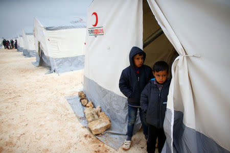 Displaced Syrian boys stand next to tents supplied by Turkish Red Crescent at Kelbit camp, near the Syrian-Turkish border, in Idlib province, Syria January 17, 2018. REUTERS/Osman Orsal