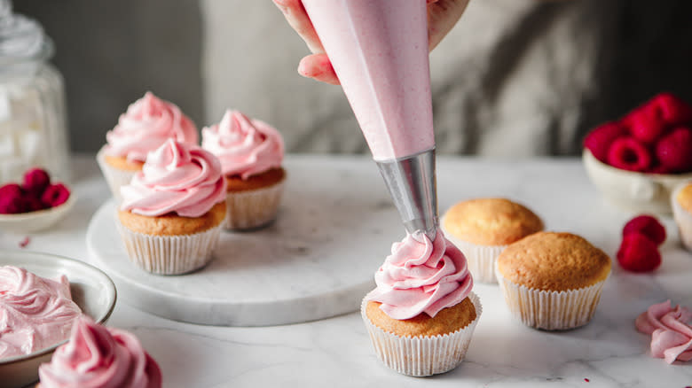 Piping pink icing onto cupcakes