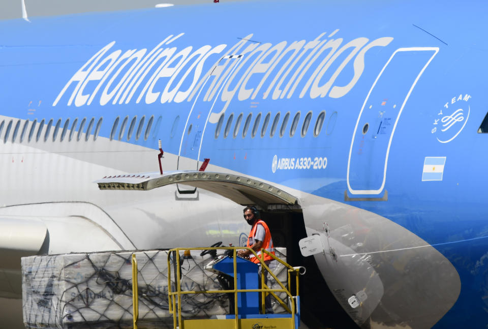 A worker unloads the first shipment of Russia's Sputnik V COVID-19 vaccine from an airplane at the international airport in Buenos Aires, Argentina, Thursday, Dec. 24, 2020. (AP Photo/Gustavo Garello)