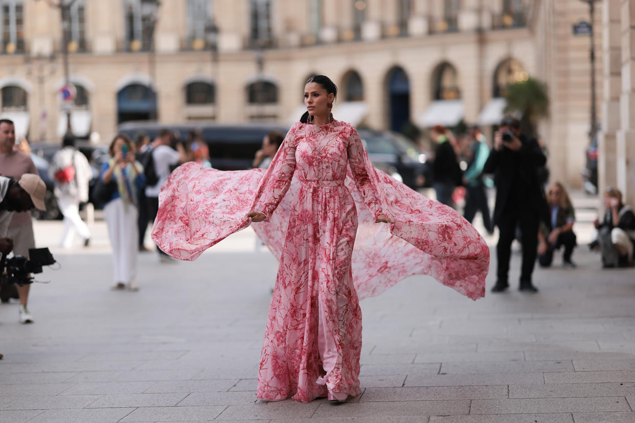 Inspiration shot: Street style star seen wearing a pink/rose maxidress with floral print, a matching cape and red huge diamond earrings, outside the Giambattista Valli Show during the Womenswear Spring/Summer 2024 as part of Paris Fashion Week on September 29, 2023 in Paris, France.